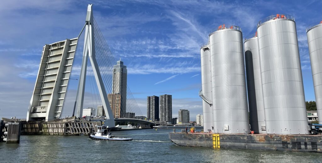 Boat carrying stainless steel tanks during transport and installation near the Erasmusbrug in Rotterdam.