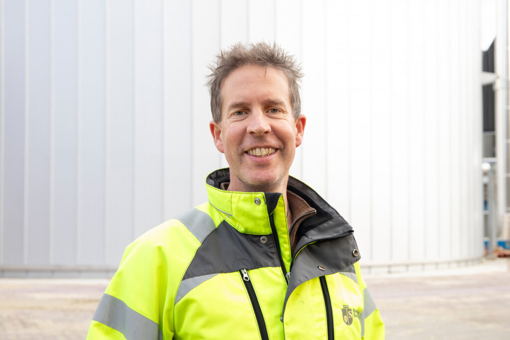 Sander Berger, project manager at Royal Swinkels, standing in front of a hot water buffer tank.